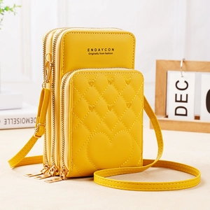 Detailed view of yellow PU leather crossbody bag with three zipper sections and quilted heart