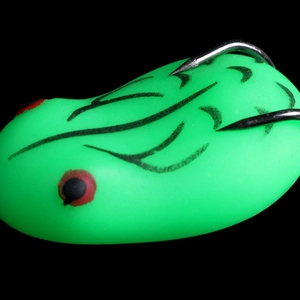 Macro shot of green floating frog lure with black stripes and metal hook on black background