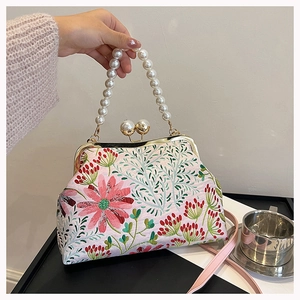 Detailaufnahme der rosa Seidentasche mit Blumenstickerei und elegantem Perlengriff