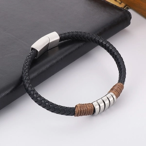 Detail of black braided leather bracelet with silver magnetic clasp and brown cord wrap