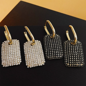 Vue détaillée de boucles d'oreilles rectangulaires avec strass noirs et blancs dorées