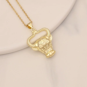 Detail of gold bull head pendant featuring intricate engraving and cubic zirconia stones
