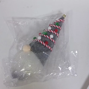 Close-up of a festive grey Christmas gnome doll with red stripes in clear plastic packaging
