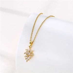 Détail macro du pendentif en forme de feuille avec oxydes de zirconium et chaîne en or