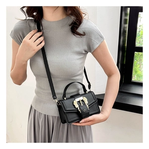 Model showing a black crossbody bag with a luxury lion head buckle and golden hardware