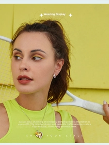 Model wearing yellow heart gemstone pendant necklace and floral earrings in sunny studio