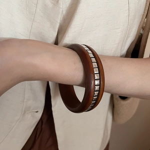 Détail d'un bracelet en bois avec clous carrés argentés porté au poignet avec style