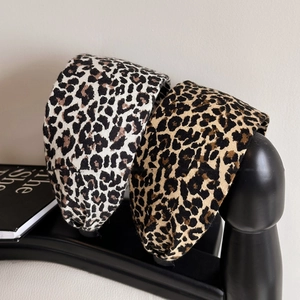 Fashionable leopard print wide headbands in white and brown fabric displayed on a stand