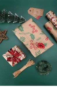 Flat lay of vintage kraft Christmas gift wrap with holly leaves and red ribbon ties