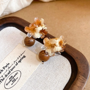 Détail de boucles d'oreilles fleurs en résine et perles de bois sur support tissu