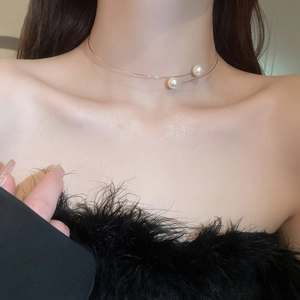 Detail of minimalist gold choker necklace with two white pearls on model collarbone