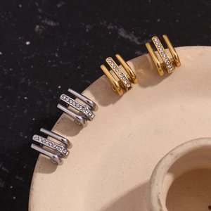 Detail view of gold and silver triple-layered J-shaped stud earrings with crystal rhinestones