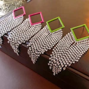 Macro shot of long geometric fringe earrings with rose red and neon green crystal studs