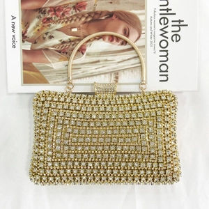 Detail shot of a champagne gold evening clutch with rhinestones and metal handle