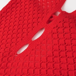 Détail macro du tissu en maille rouge avec motifs ajourés et texture de tricotage