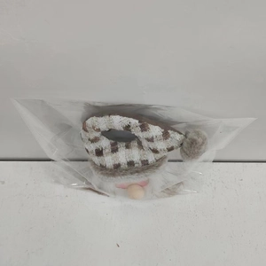 Close-up of a Christmas gnome doll with a plaid knit hat and faux fur beard in packaging