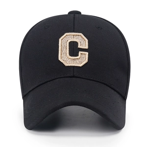 Black baseball cap with gold embroidered letter C and pineapple textured fabric