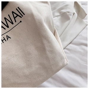 Nahaufnahme der cremefarbenen Canvas-Stoffstruktur mit schwarzem Hawaii-Druck auf Tasche