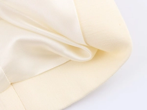 Detail of premium creamy white fabric showing smooth satin lining and woven texture