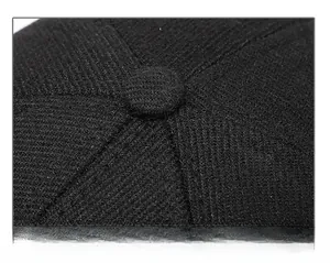 Close-up of the reinforced stitching and top button on a black winter baseball cap