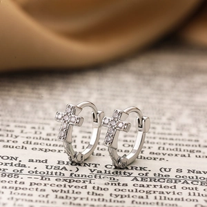 Vue macro de boucles d'oreilles croix en argent avec zircons sur pages de livre