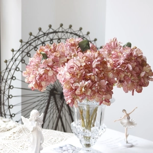 Detailed view of pink and lilac artificial hydrangea bouquet in a clear glass vase