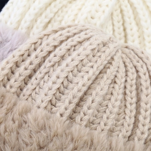Nahaufnahme dicker Strickmützen mit weichem Kunstpelzbesatz in Beige und Helllila
