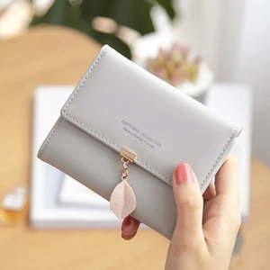 Detail of grey PU leather tri-fold wallet with leaf pendant and brand lettering