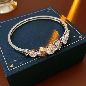 Detail of silver bangle with five oval zircons on a blue jewelry gift box
