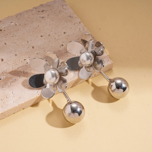 Silver flower earrings with white pearls and metal spheres on stone pedestal