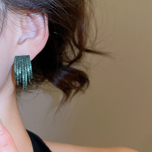 Close-up of green crystal multi-layer C-shaped fringe earrings worn by a model