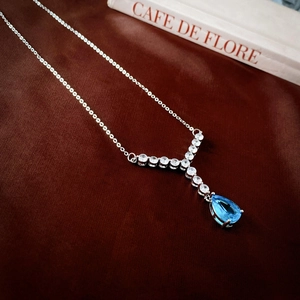 Vue détaillée du collier en Y avec une pierre précieuse bleue poire sur velours foncé