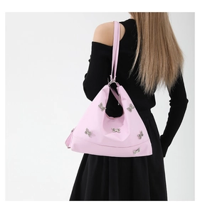 Detailed view of pink shoulder bag with silver butterfly charms worn by a model