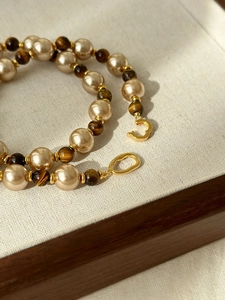 Detailed macro of 925 silver clasp on tiger's eye and pearl beaded necklace