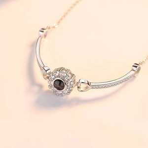 Macro view of silver sunflower pendant with black projection stone and diamond accents