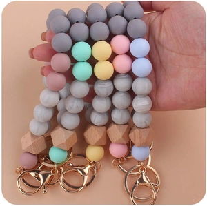 Detail view of four handheld silicone beaded keychains with wooden beads and gold rings