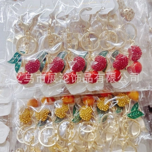 Detail of cherry keychains with rhinestones and green enamel in original packaging