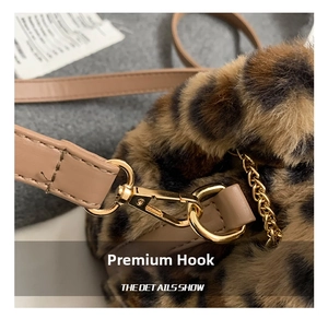 Close-up of golden metal hooks and leather straps on plush leopard bucket bag