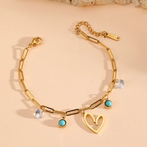 Detail of gold paperclip chain bracelet featuring a heart charm and turquoise beads