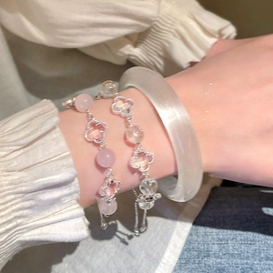 Close-up of pink and clear crystal four-leaf clover bracelets and a smooth white bangle