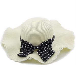 Detalle de sombrero de paja beige con cinta de cuadros y gran lazo decorativo