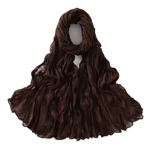 Close-up detail of dark brown pleated cotton scarf texture and natural wrinkled fabric