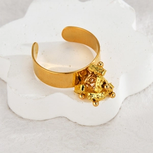 Adjustable gold stainless steel ring with textured metal blocks and beads on floral stand