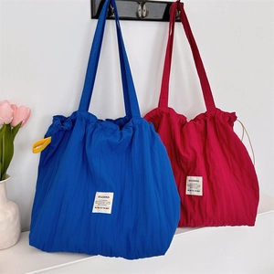 Détail de grands sacs fourre-tout à cordon avec texture plissée et écusson de marque