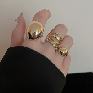 Detail view of gold bean ring and multi-layered band with metallic ball charms