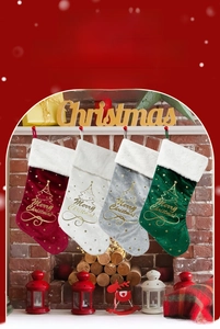 Détail de chaussettes de Noël en velours avec motif d'arbre doré sur une cheminée rouge