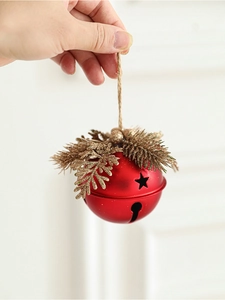 Close-up of red Christmas bell ornament with gold pine needles and star cutouts
