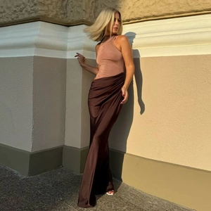 Détail d'une robe longue sans manches avec bustier beige et jupe plissée marron