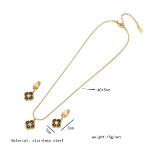 Detail view of gold stainless steel necklace and earrings set with black clover charms