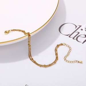Detail of a gold double-layer beaded chain bracelet with adjustable lobster clasp
